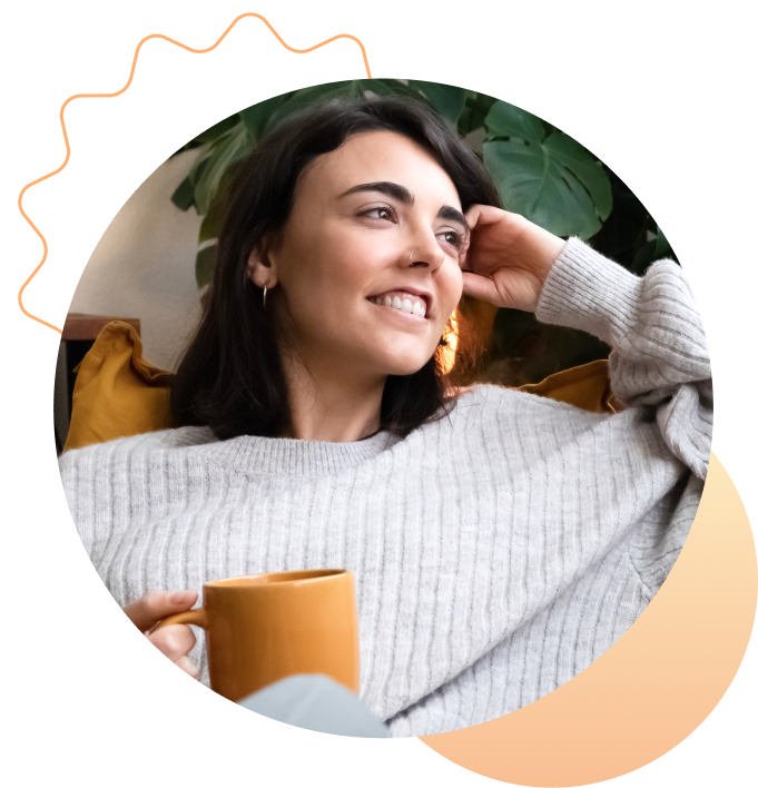 A person smiling at home while holding a warm mug