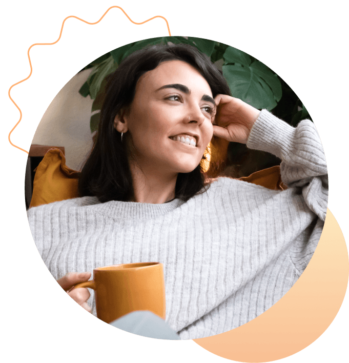 A person smiling at home while holding a warm mug