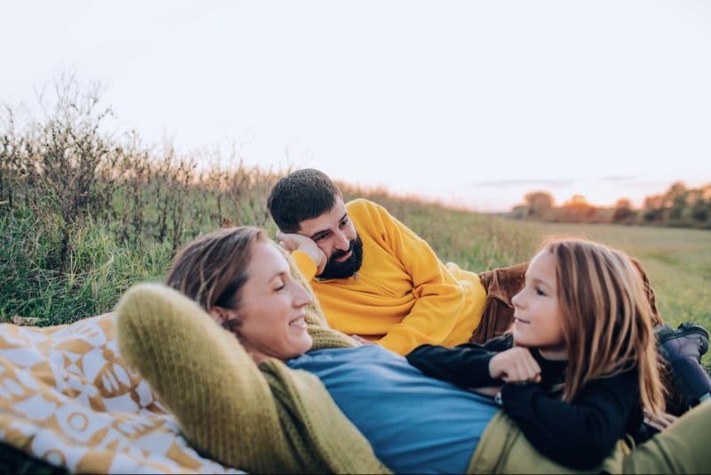 A family relaxing together in a field at sunset