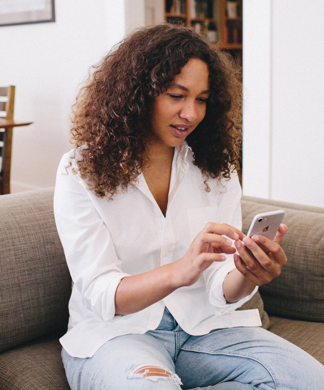 Woman sitting on couch looking at phone