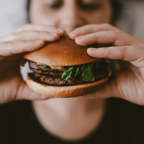 Man holding and taking a bite of a hamburger