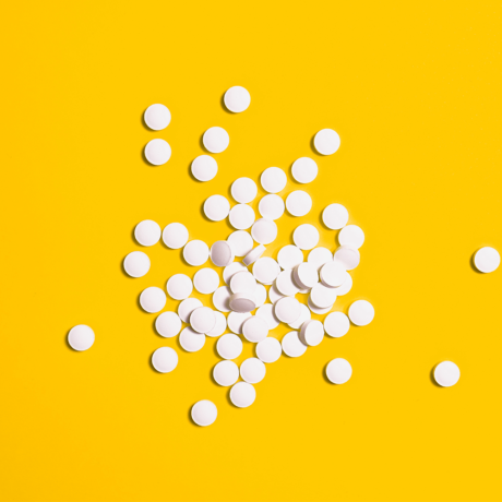 White pills laying on a yellow surface