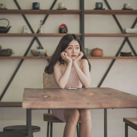 Woman holding her head up while sitting at a table in a store.