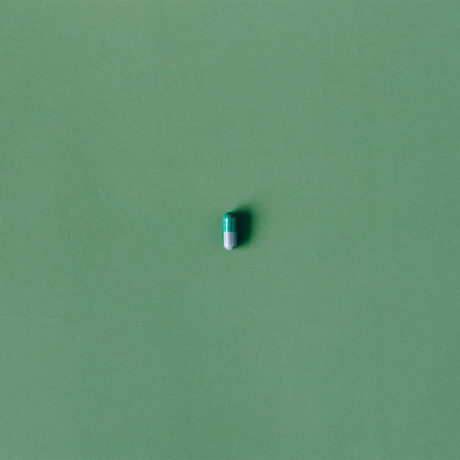 A single prozac pill against a green background