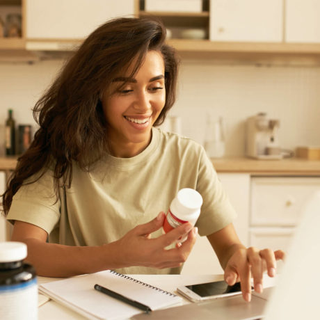 Woman smiling and holding bottle of prescription pills