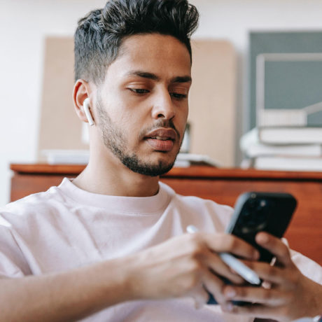 man sitting at desk looking at phone