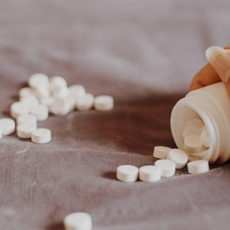 close up of a hand holding a bottle of prescription pills