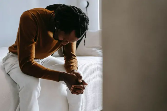 man sitting on a bed looking at his hands